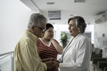 Sad Female doctor talking to older couple