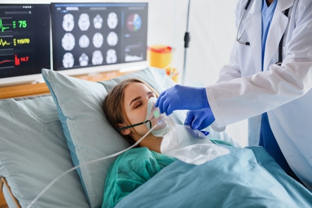 Doctor administering oxygen mask to woman with brain scans behind