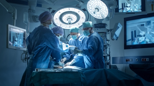 Four doctors wearing blue scrubs in operating room