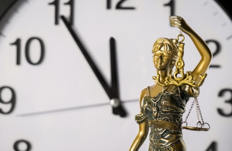Lady justice holding scales in front of clock